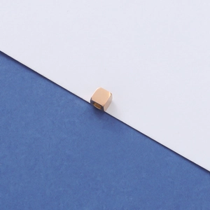 Macro-opname van een gepolijste gouden vierkante kraal voor DIY-sieraden maken