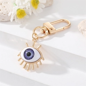 Detail of evil eye keychain with blue resin eye and golden metal lash accents