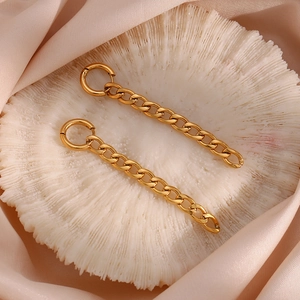Macro d'une boucle d'oreille pendante chaîne Figaro en acier doré sur soie