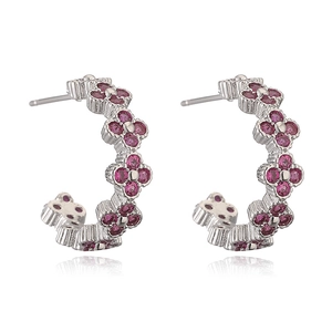 Macro detail of C-shaped flower earrings featuring vibrant magenta crystals and silver base