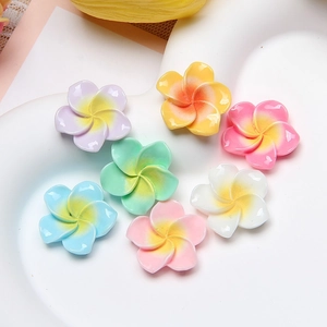 Colorful resin plumeria flower charms displayed on a heart tray for DIY crafts