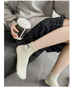 Close-up of beige cotton crew sock featuring a small embroidered panda near the cuff