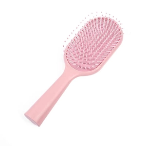 Pink macaron cushion hairbrush with anti-static bristles for scalp massage on white background