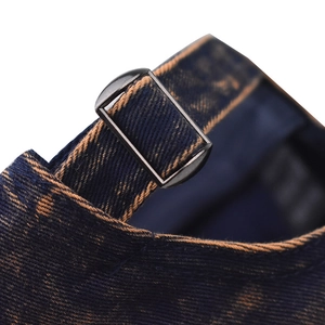 Detail of adjustable metal buckle and contrast stitching on washed denim baseball cap