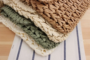 Close-up of handmade woven straw bags in khaki and beige on a rustic wooden table