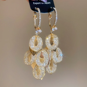 Close-up of golden leaf tassel earrings with sparkling cubic zirconia and starburst effects