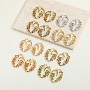 Macro detail of leaf hoop earrings featuring colorful pavé zircon on monstera leaf design