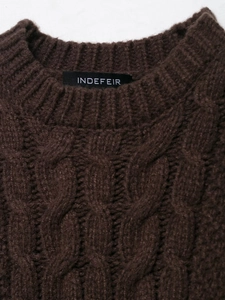 Detail of the round neckline and complex cable knit texture on dark brown sweater