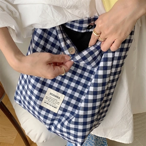 Détail du sac cabas en toile à carreaux bleus et blancs avec étiquette tissée minimaliste