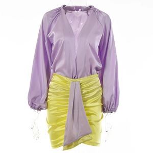 Dettaglio di camicia in raso lavanda e minigonna a pieghe gialla su un manichino