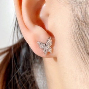 Close-up of elegant silver bowknot earring with micro-paved zircons worn by model