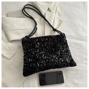 Detail of black sequin shoulder bag with sparkling texture and thin shoulder strap