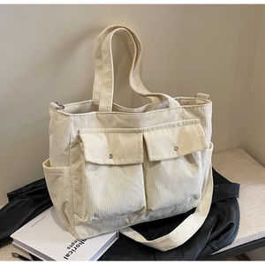 Detail of cream corduroy tote bag with dual front snap pockets and adjustable strap