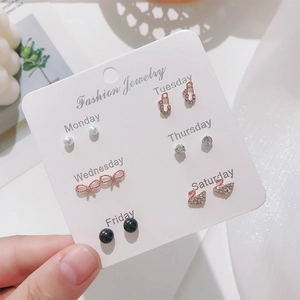 Close-up of 6 pairs of rose gold stud earrings featuring pearls and crystals on a white card