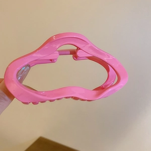 Détail de la pince à cheveux ondulée rose vif avec une finition brillante en acrylique