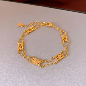 Detail of a double-layered gold bracelet with hollow star charms and heart pendant