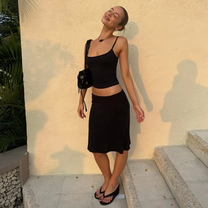 Vue complète d'une femme portant un ensemble haut à bretelles noir et mini-jupe