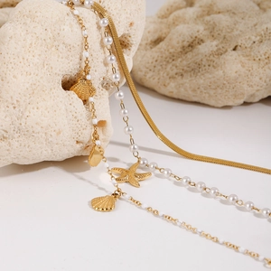 Gold layered necklace set with starfish and shell pendants on coral stone base