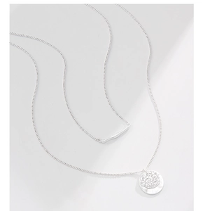Detail of silver double layered necklace with textured round disc and bar pendants