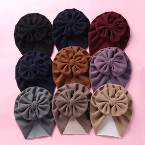 Detailed close-up of soft cashmere-like baby hats with large bows in nine various colors