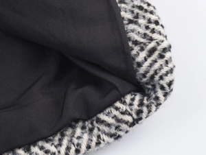 Gros plan du manteau en laine à chevrons noir et blanc avec doublure noire lisse et douce