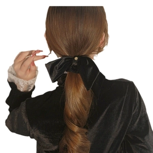 Elegant large black velvet bow hair scrunchie with gold buckle on model's ponytail