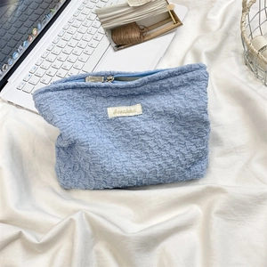 Detail of blue bubble textured cosmetic bag with metal zipper on a white fabric background