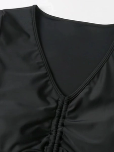Detail view of black bikini top featuring deep V-neck and ruched central texture