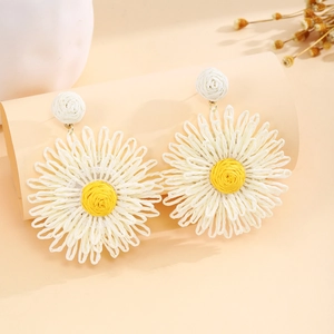 Detailed view of handmade woven raffia daisy earrings with white petals and yellow centers