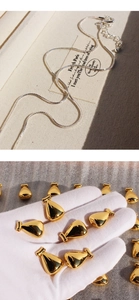 Detail view of silver snake chain with golden teardrop pendants held in white gloves