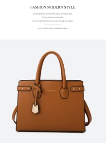 Detail of brown litchi pattern leather handbag with gold hardware and hanging ornament