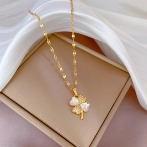 Macro view of gold clover necklace with iridescent and pavé petals on silk
