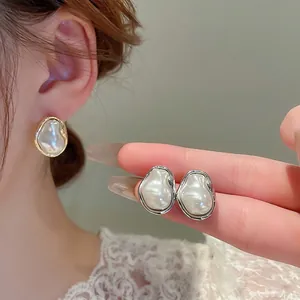 Baroque irregular pearl stud earrings with metallic gold and silver streamlined frames