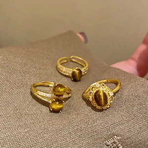 Dettaglio macro di anelli placcati oro con pietra occhio di tigre e fascia regolabile