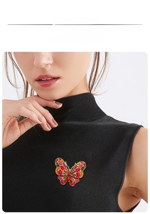 Detailed product display of a vibrant butterfly brooch with colorful rhinestones on a black knit
