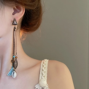 Detail of bohemian tassel earrings with turquoise beads and shell on a model