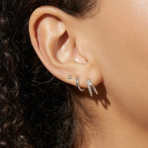 Close-up of S925 sterling silver earring set featuring studs and hoops on model ear