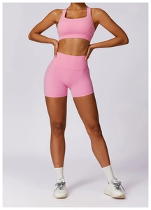 Front full body view of woman in pink yoga set including sports bra and high waist shorts