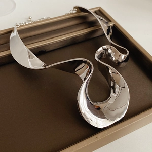 Detailed view of silver irregular geometric pendant necklace in a brown jewelry display box