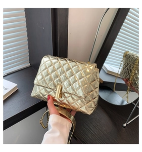 Close-up of golden quilted leather bag featuring metal chain and cylinder twist lock