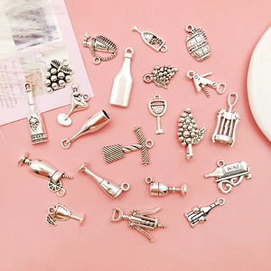 Macro shot of silver wine-themed charms including bottles and glasses on pink background