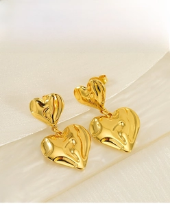 Detailed macro view of layered gold heart earrings with liquid metal rippled texture