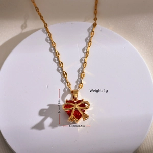 Elegant gold-plated red heart necklace with bow pendant on a minimalist background