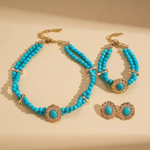 Detail view of gold floral jewelry set with turquoise beads and sparkling crystals
