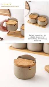 Detail of grey ceramic seasoning jars with wooden lids and high-edge anti-slip tray