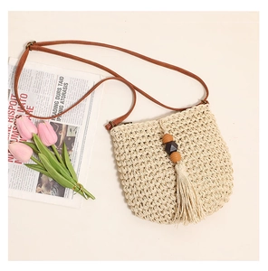 Beige woven straw crossbody bag with brown strap, wooden beads, and tassel details