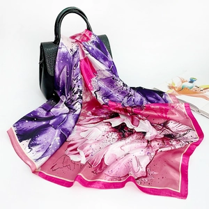 Elegant pink and purple floral silk scarf displayed with a stylish black handbag