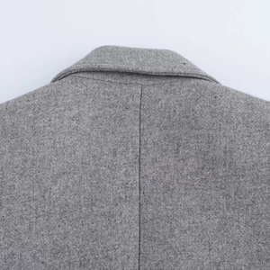 Close-up of grey wool coat neckline and back stitching detail on white background