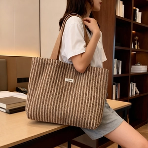 Close-up of a striped woven tote bag with V-shaped patterns and a stylish brand label