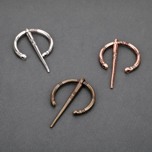 Three Viking style penannular brooches in silver, bronze, and copper metal finishes